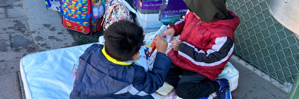 Two migrant children eating peanut butter and jelly sandwiches passed out by volunteers, and who cannot find shelter. 100 sandwiches were distributed in less than 15 minutes. 