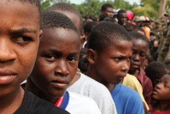 Haitian children surrounded by US military personnel 